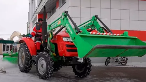 Трактор Shifeng 254 с фронтальным погрузчиком и щеткой Kerland в работе